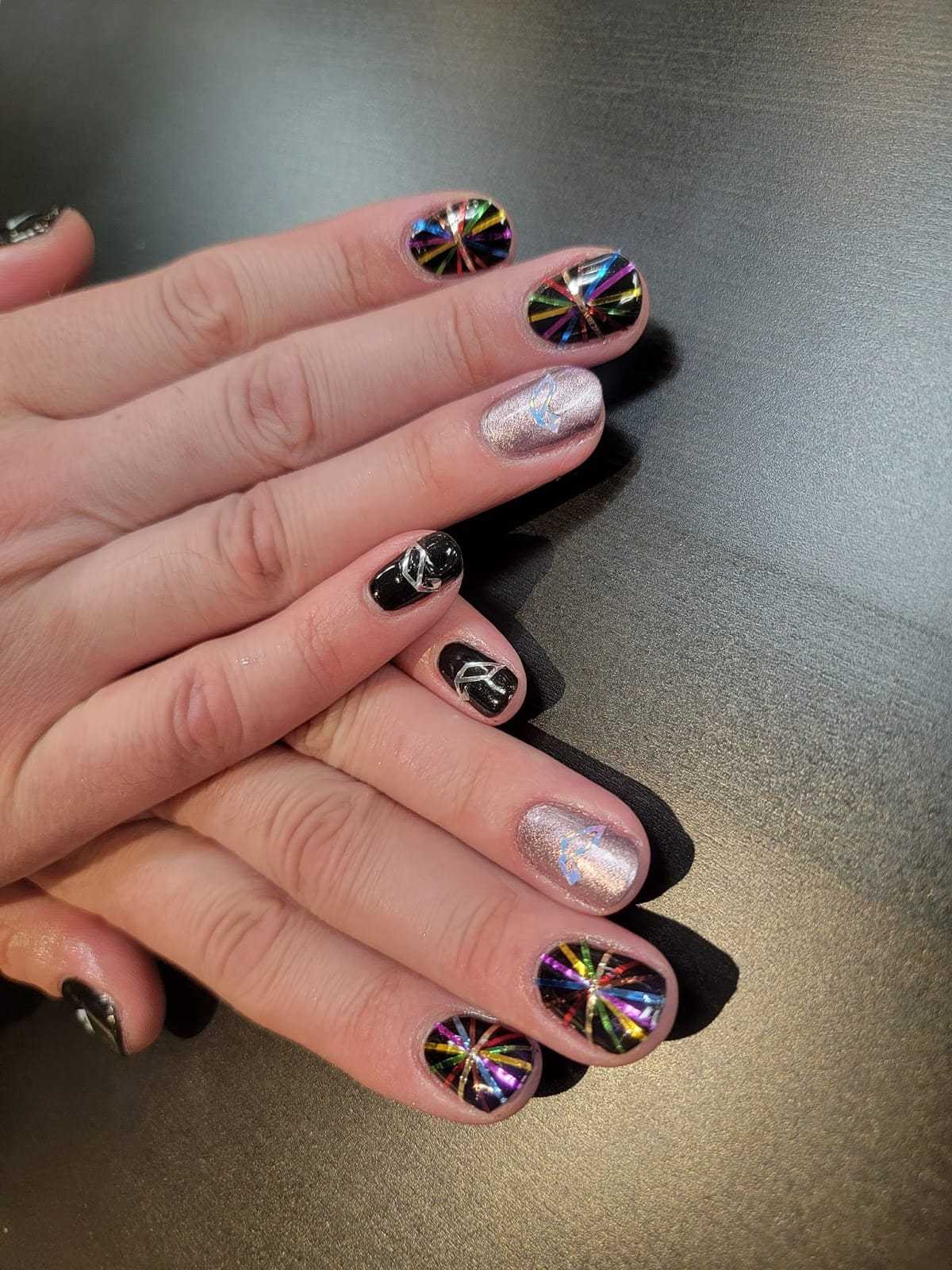 Colorful nail art with holographic and black designs on manicured hands.