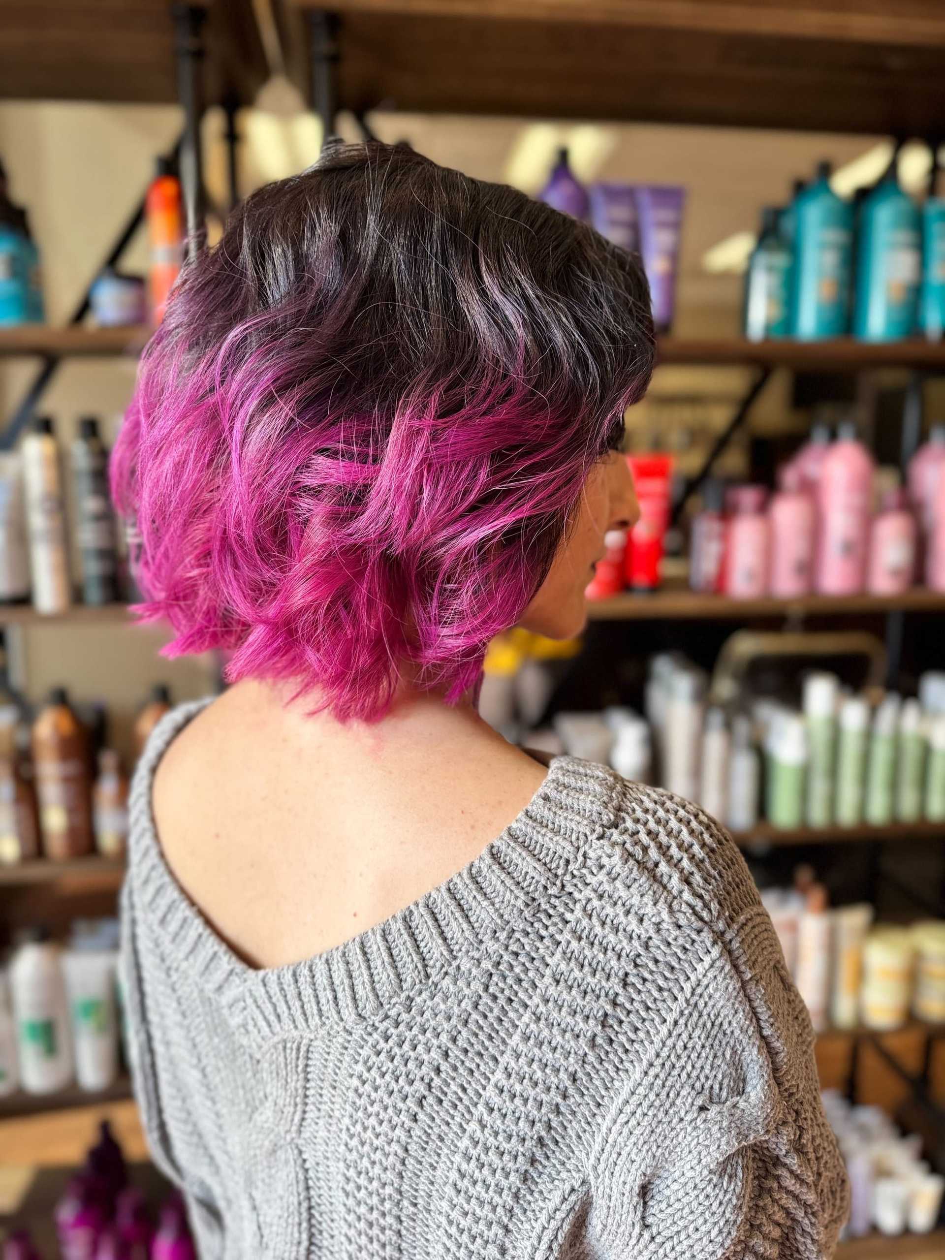 Short-haired woman with vibrant pink ombre at a salon.